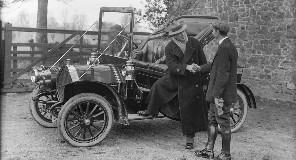 Two White men shaking hands by a car, 1920s, old photo