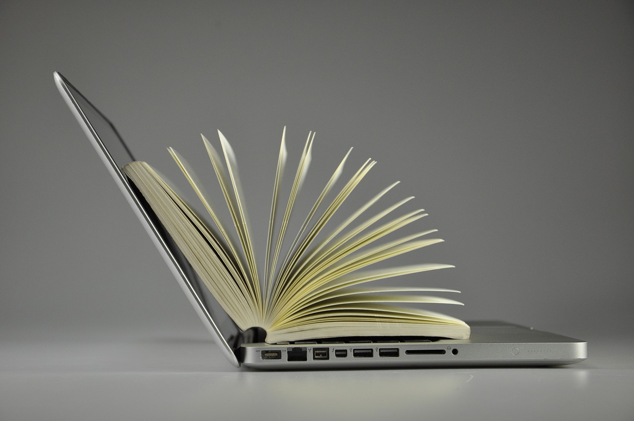 Do we still need books? Open book on top of open laptop