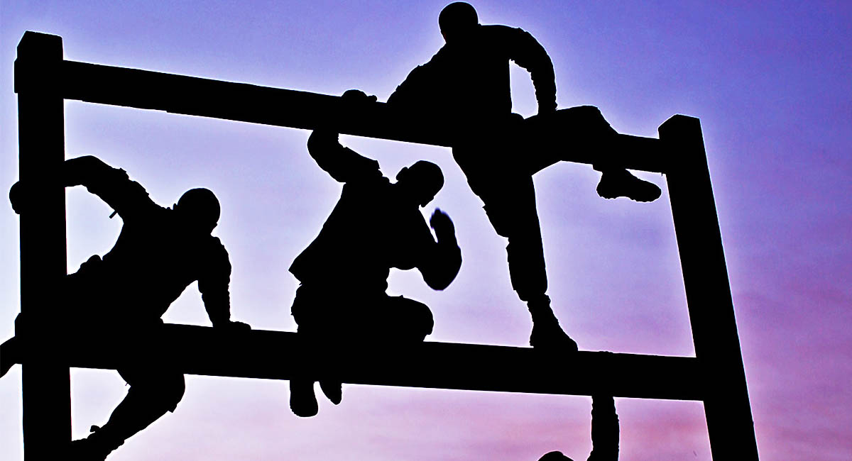 Silhouette of men climbing rails in obstacle course