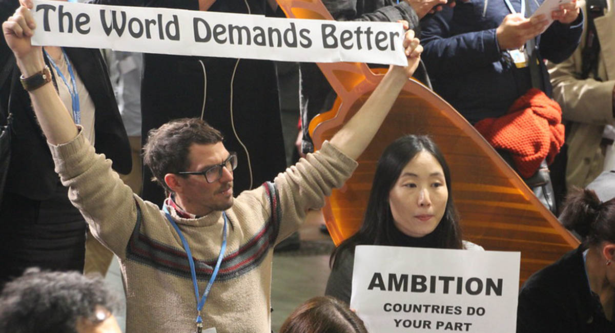 Man and woman holding protest signs at a rally