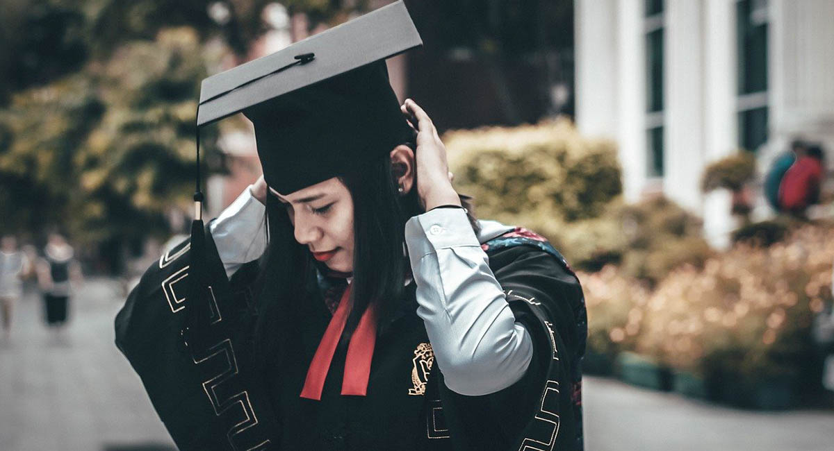 Young woman wearing graduation gown and mortar board