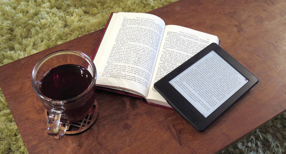 eBook reader resting on top of a physical paperback book