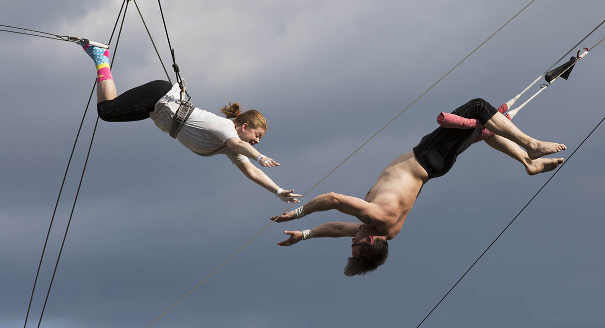 Woman learning trapeze with man catching her