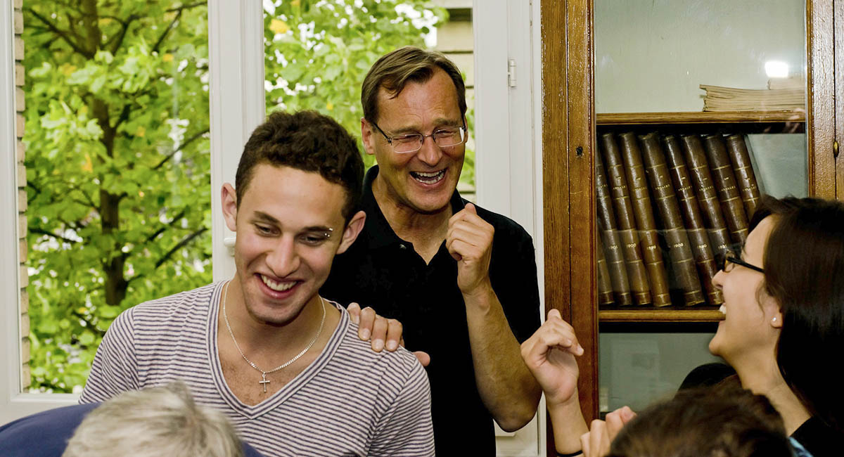 young white man and two white adults in room laughing