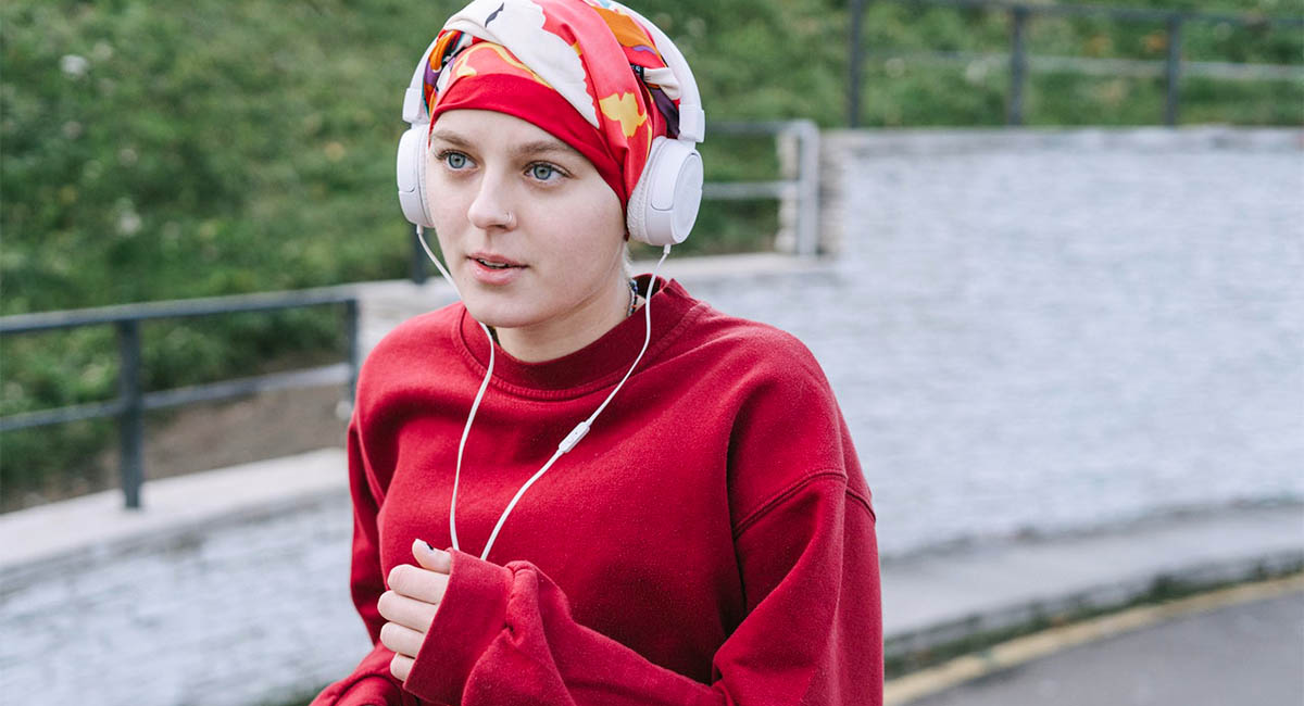 Young woman jogging with headphones on, red