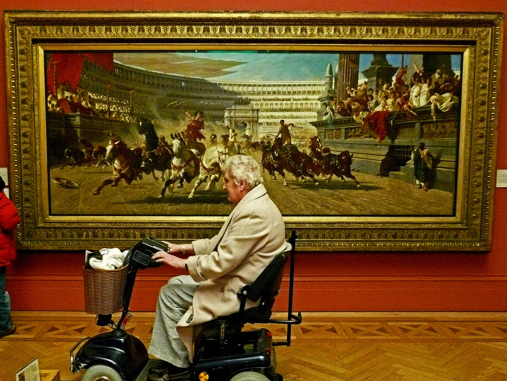 Art makes life worth living. Older woman in a wheelchair in front of large artwork