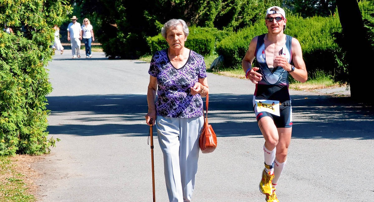 Older woman walking and younger man running on path