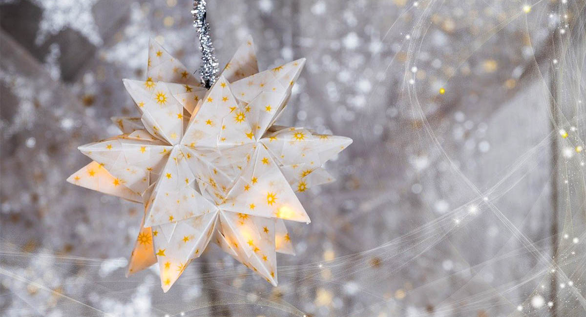 Paper star hanging in front of blurred strings of lights