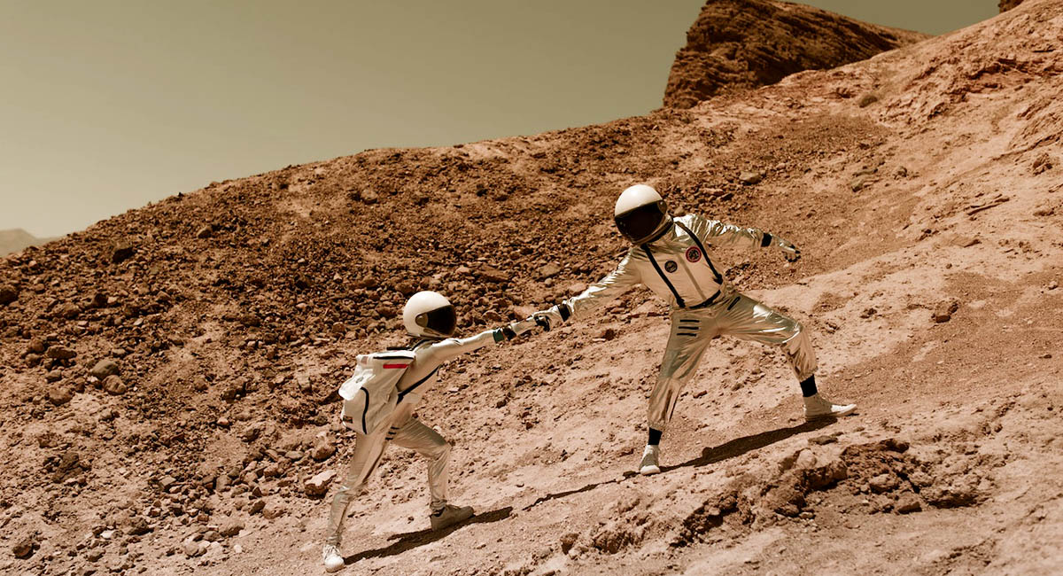 two people in space suits climbing a hill brown and green