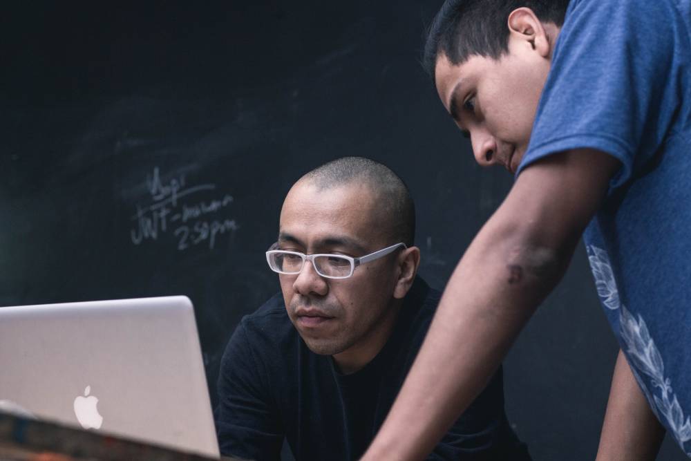 I'm happy to help! One man helping another on a computer