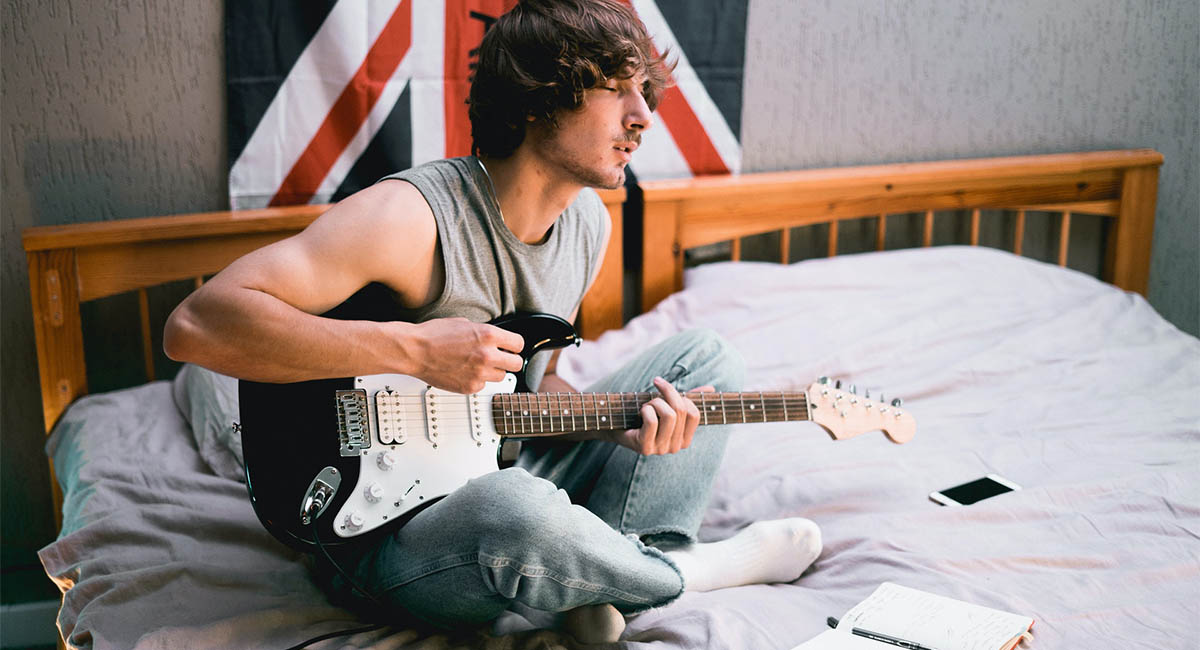 Young man on bed playing guitar