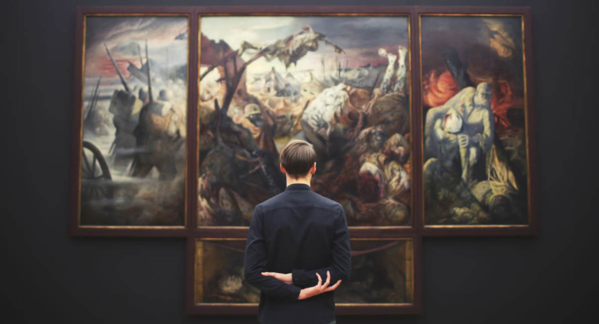 White man standing in front of wall-sized classical painting