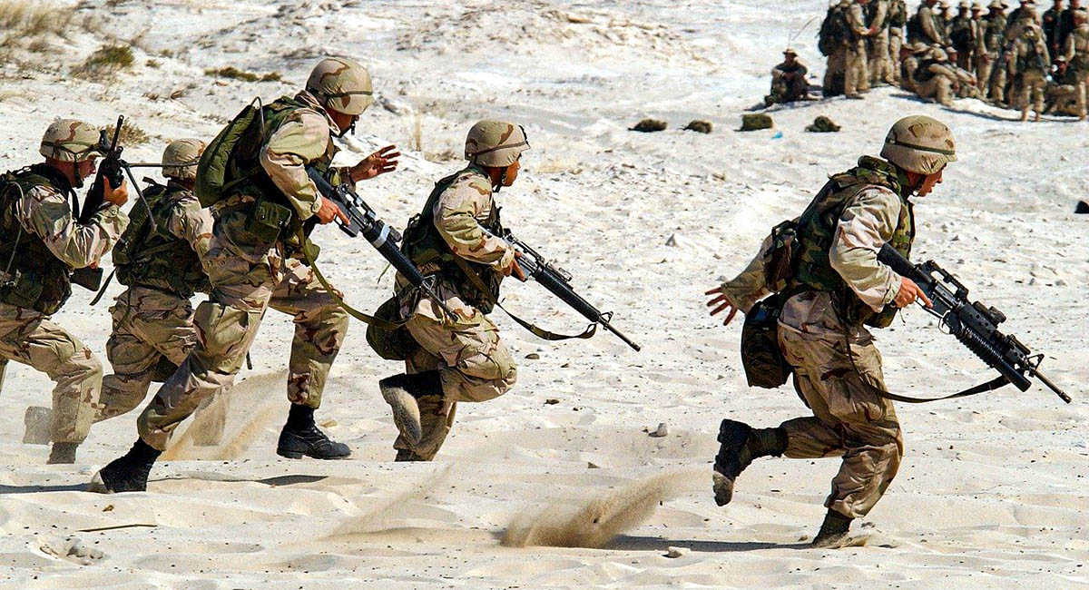 Soldiers running with guns in desert