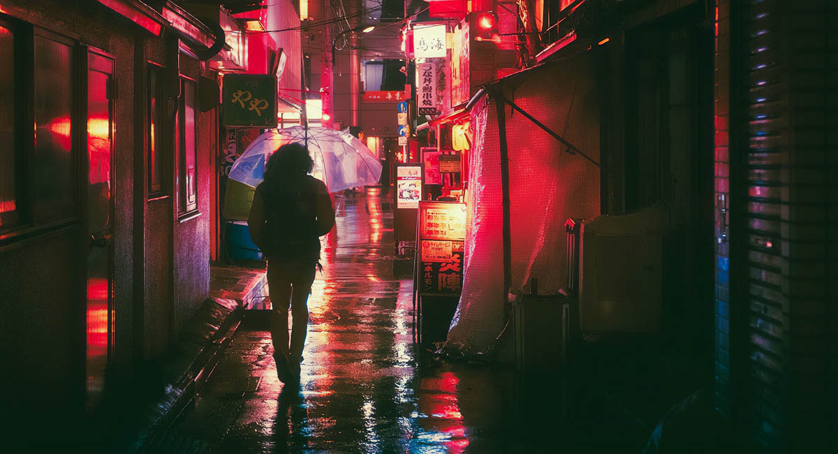 person walking down a street at night in Osaka