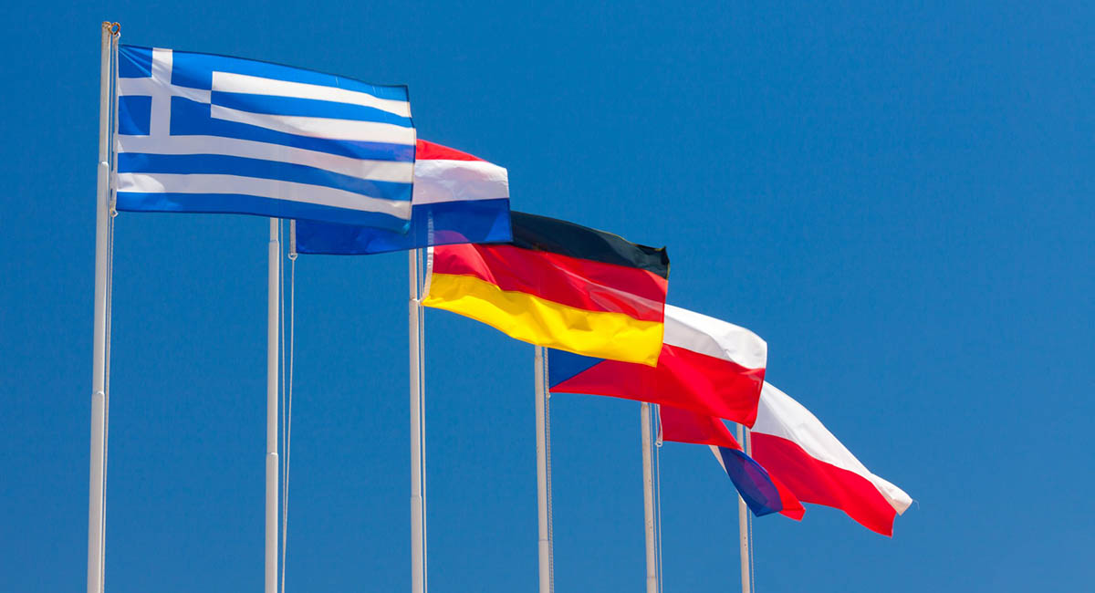 Flags of different nations flying in a deep blue sky