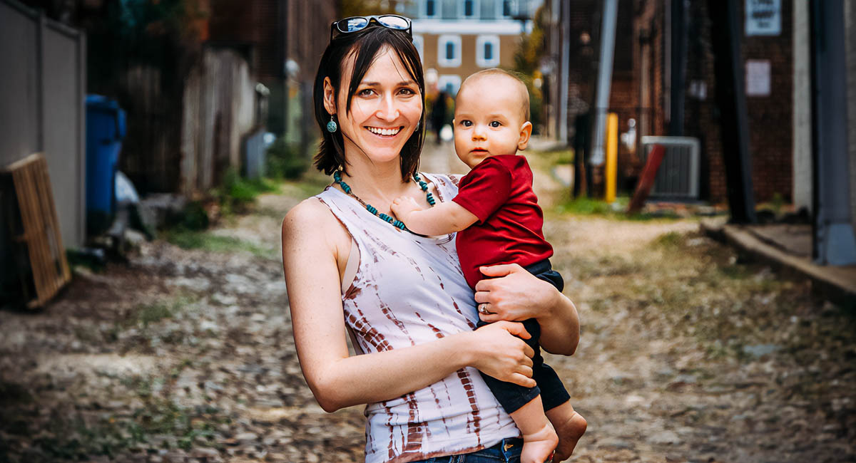 woman holding baby in alleyway