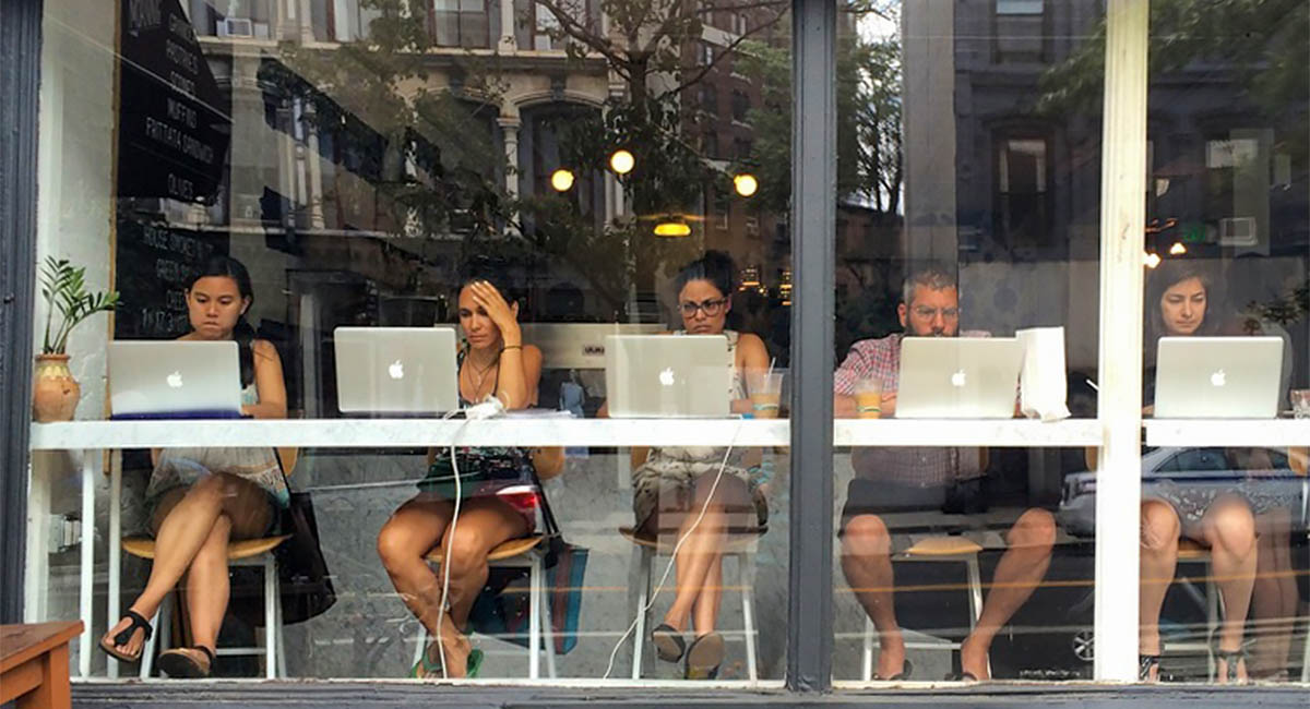 people on laptops in cafe window