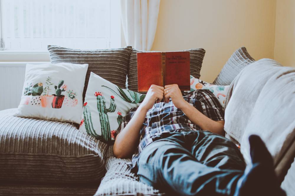 Time to read Person lying on a couch with a book in front of their face