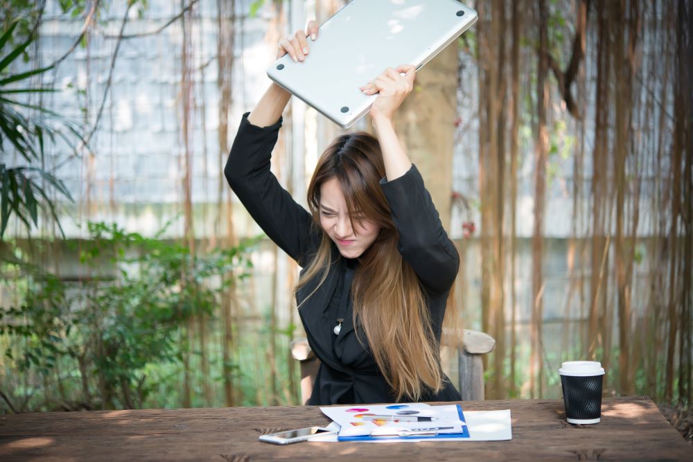 I can't take it anymore! Woman throwing laptop in frustration