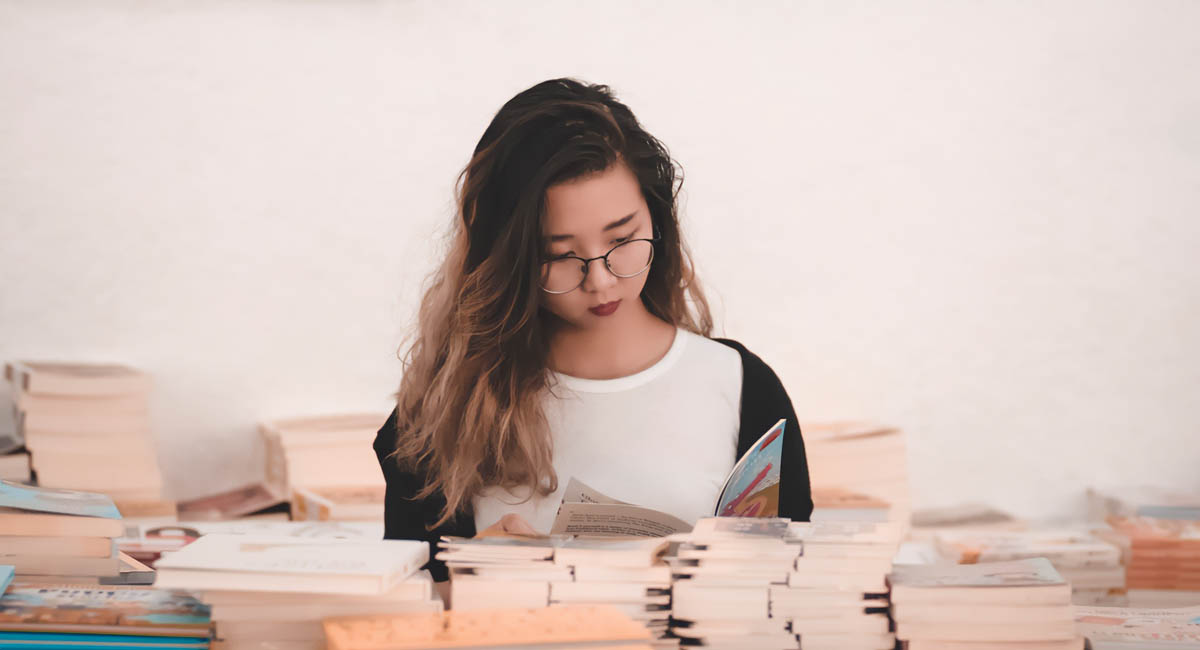 Young woman reading surrounded by books