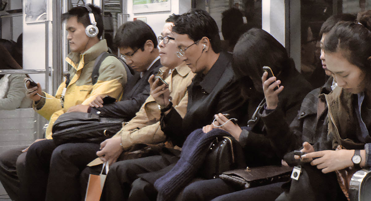 People on commuter train with smartphones, Korea