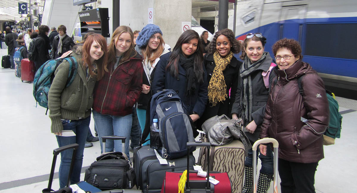 Diverse young women and one older woman in French train station with luggage