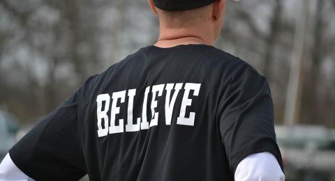 Man facing away in t-shirt that says "BELIEVE" on the back