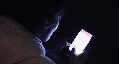 Woman looking at bright cellphone at night