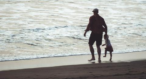 Silhouette of man with child on beach