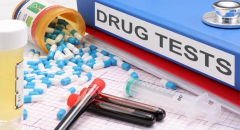 Drugs, test tubes, syringe, notebook with label "DRUG TESTS"