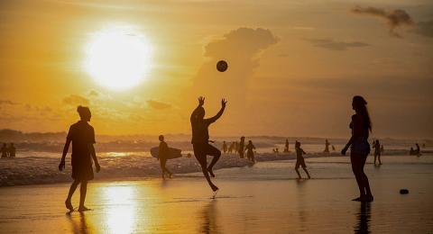 Silhouettes of people playing beach volleyball at sunset