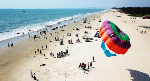 birds-eye view of people on a beach with large kite in the foreground