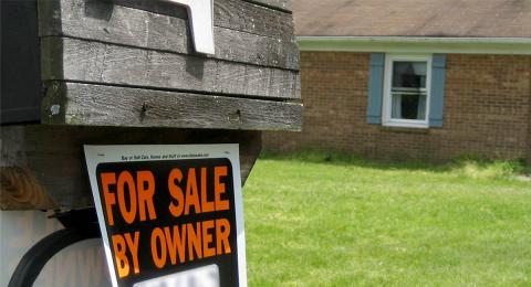 FOR SALE BY OWNER sign in front of house