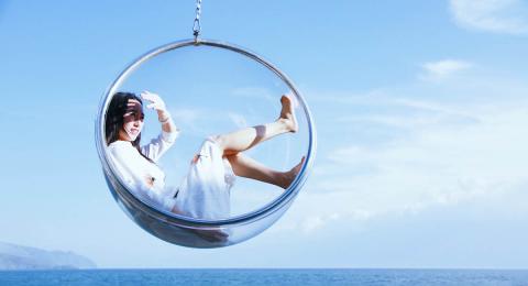 woman sitting in hanging glass circle chair