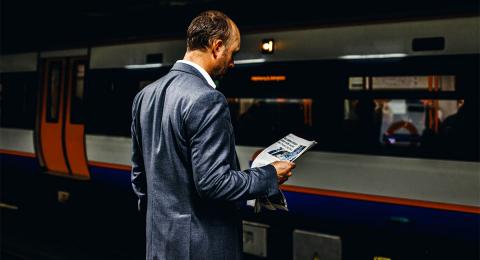 Businessman reading a newspaper while waiting for a subway train 