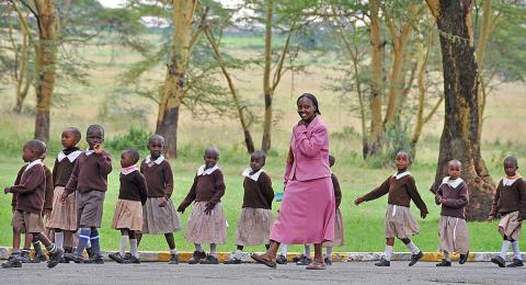 Teacher and students in Kenya, Africa, walking in a line outdoors