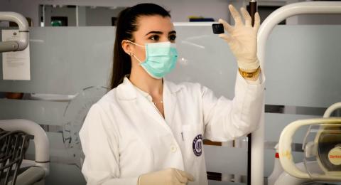 Young White female medical assistant viewing a small slide