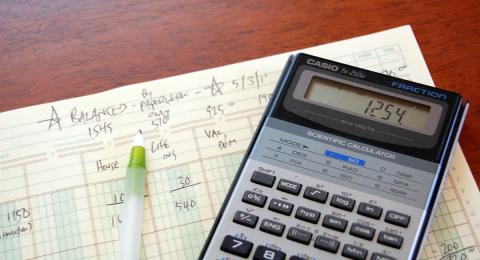 calculator and pen on top of account ledger
