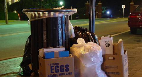 overflowing trash bin on city street at night