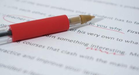 Red pen lying on paper with corrections to text