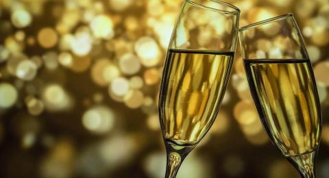 two champagne glasses touching, gold bokeh background