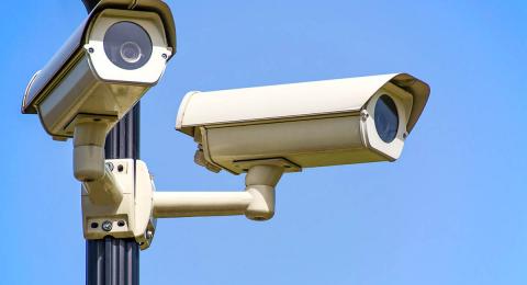 two security cameras on pole with blue sky background