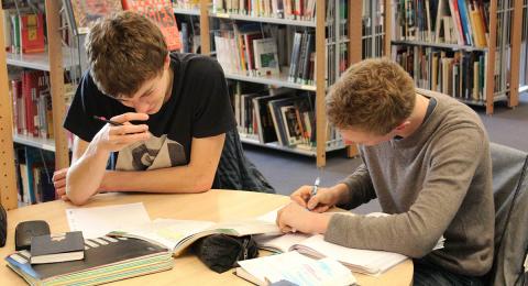 Two White male students at table in library