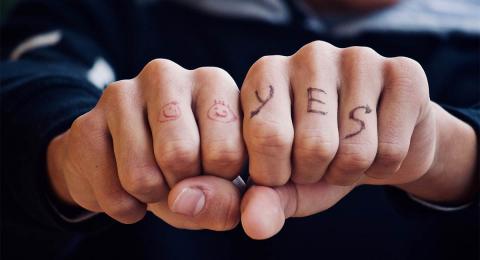 man's fists with happy faces and yes written on knuckles