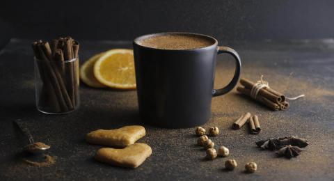 mug with liquid and cinnamon sticks on dark background