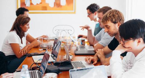 Group of young businesspeople working together at table with computers