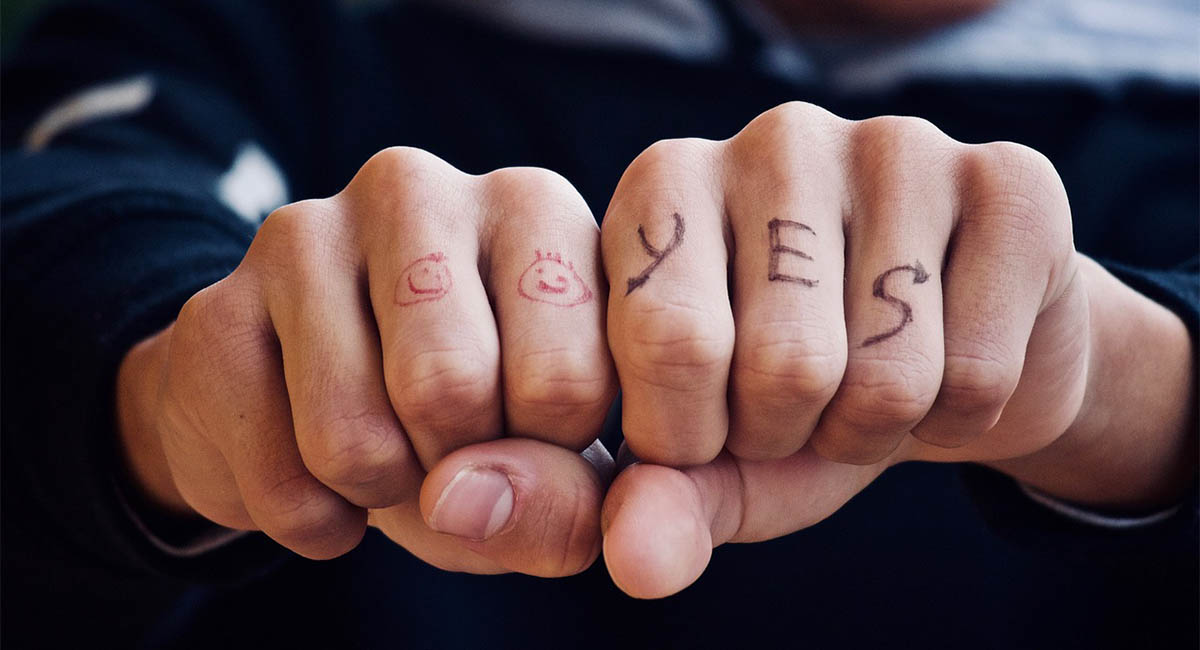 man's fists with happy faces and yes written on knuckles