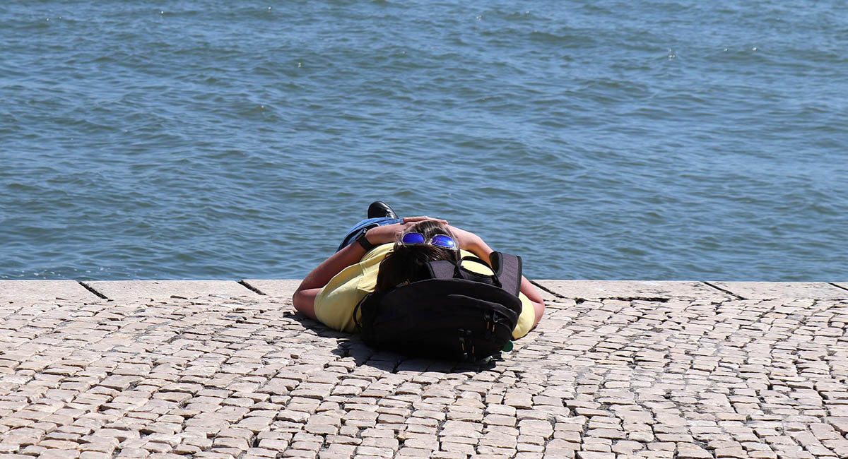 person lying on boardwalk by water