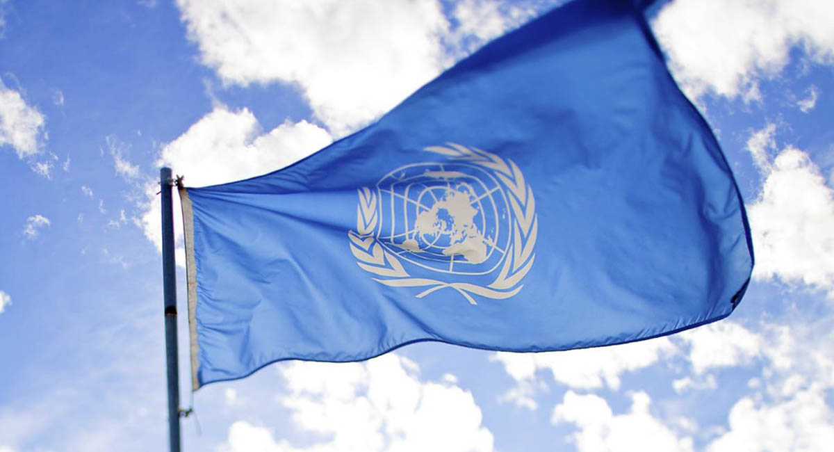 United Nations flag flying with blue sky and clouds background