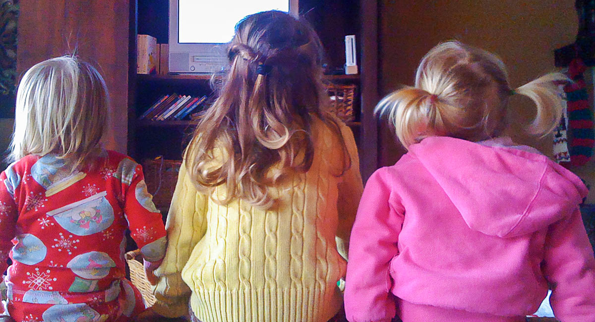 three children sit and watch old tv set